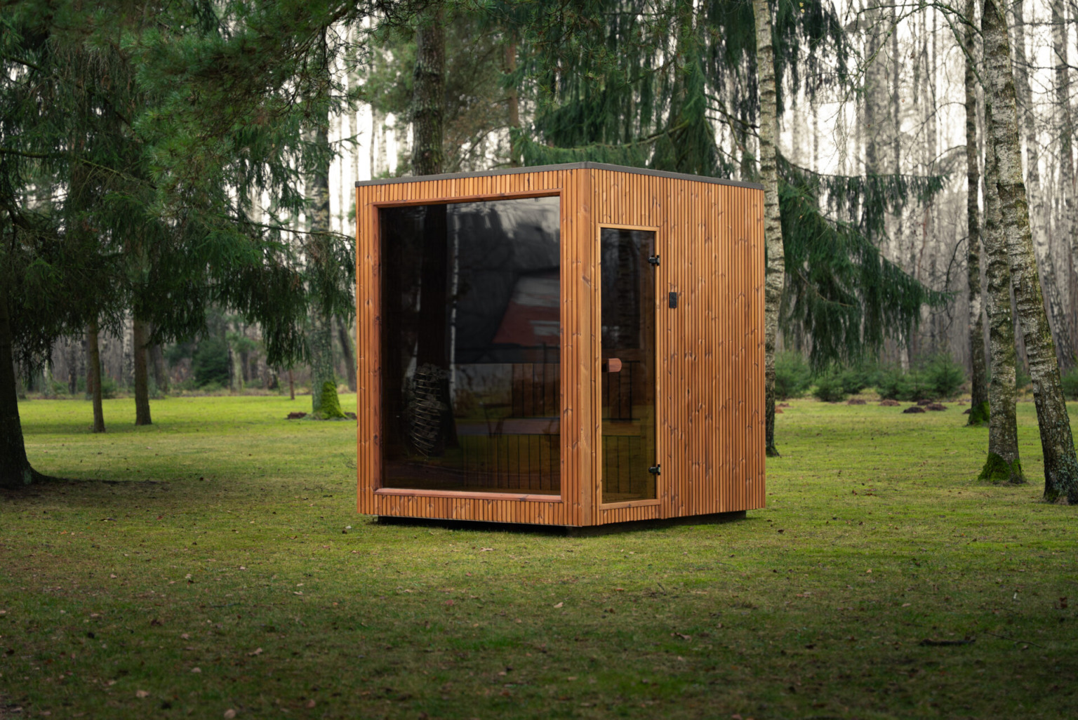 Timber sauna cabin with a glass front on a lawn among trees